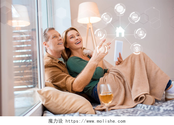 一对夫妻坐在了地毯上微笑的看着前方微笑的妻子拿着数字平板电脑, 而坐在地板上与丈夫, 智能家居的概念